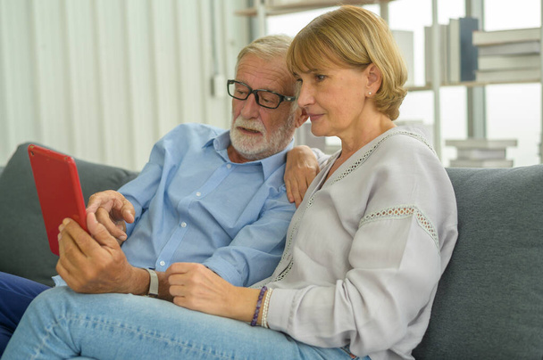 Senior caucasian couple using tablet sitting on sofa - Foto, Imagem