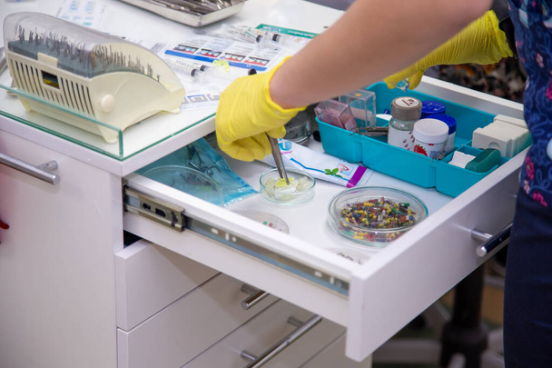 Eine Krankenschwester, die mit einer medizinischen Schublade arbeitet, bereitet ein Werkzeug für die Arbeit vor - Foto, Bild