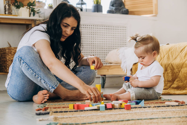 Early childhood development. Communication between mother and child. Love and kindness in the family. The kid plays with wooden eco-friendly toys. - Photo, Image