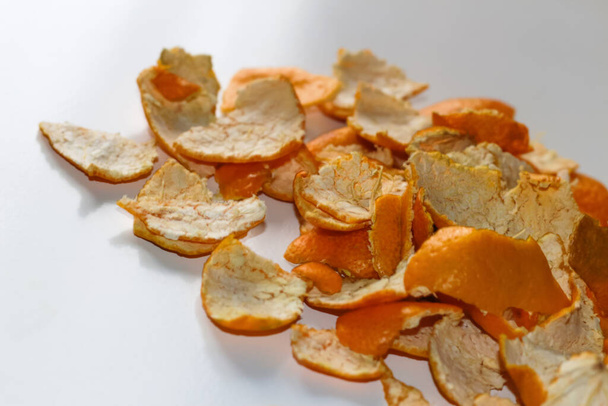 Defocus modern trendy bright Christmas background from the peels of orange and tangerine on a white background. Many small pieces of dried peel. Orange bright color. Pile. Out of focus. - Photo, Image