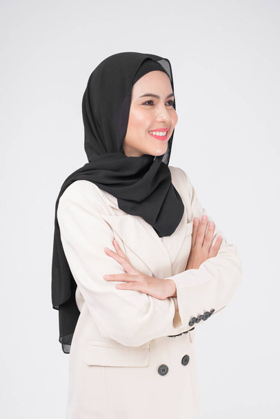 Portrait of young smiling muslim businesswoman wearing suit with hijab over white background studio.	 - Photo, image