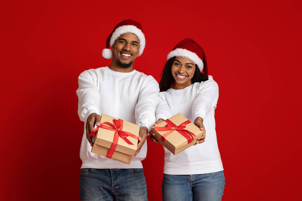 Loving Afrikaans Amerikaans paar in Santa hoeden met geschenkdozen - Foto, afbeelding