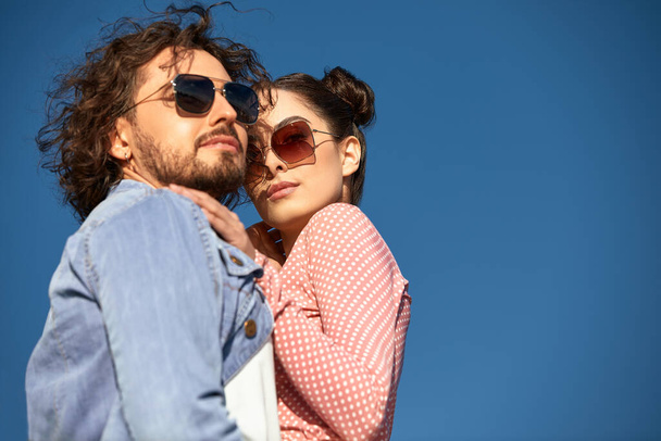 Fashion models couple wearing sunglasses. Sexy woman and handsome young man portrait over light background. Attractive fashion Boy and girl posing. Hairstyle, haircut, glasses - Photo, Image