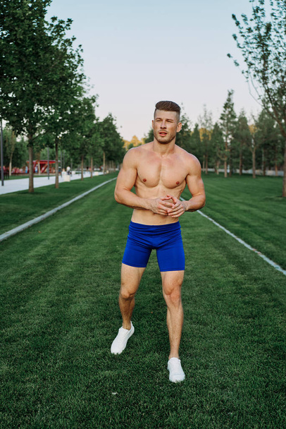 athletic man with a pumped-up torso exercise in the park fitness - Photo, image