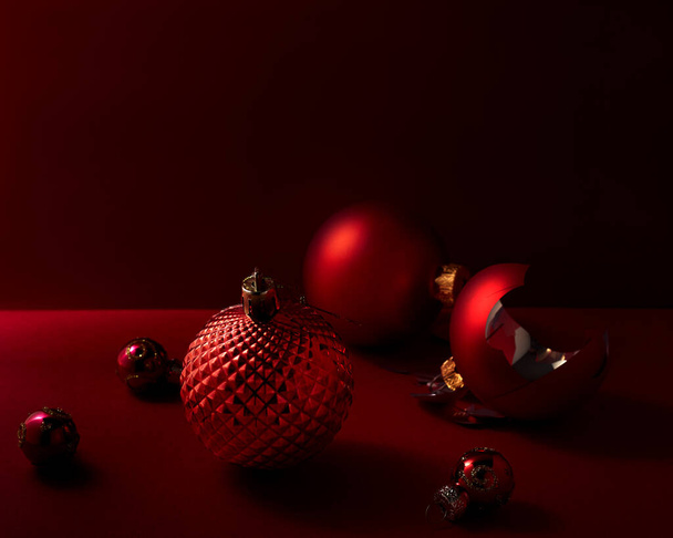 Juguetes rojos de Navidad sobre fondo rojo. Una bola está rota. Enfoque selectivo - Foto, imagen