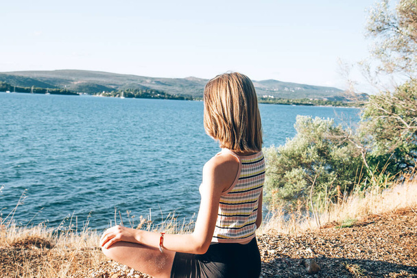 Giovane bella ragazza adolescente meditando sulla riva del mare e gode il paesaggio - Foto, immagini
