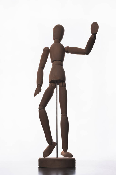Drehbares Holzmodell eines Mannes auf einem Metallständer mit erhobener Hand, der zur Begrüßung winkt. - Foto, Bild