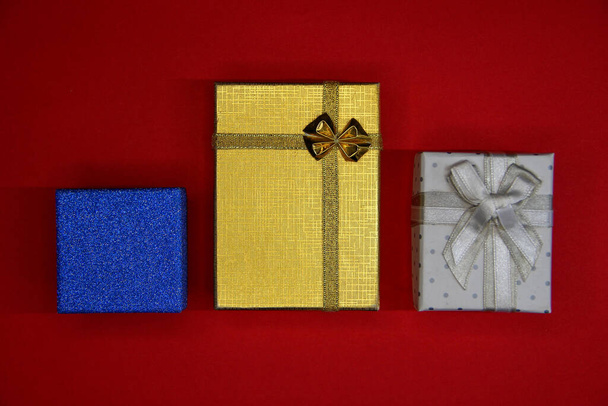 Drie veelkleurige geschenkdozen op de rode achtergrond - Foto, afbeelding