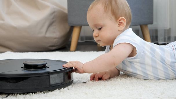 新しいロボット掃除機の小さな赤ちゃんの男の子のキュリオスの閉鎖 - 写真・画像