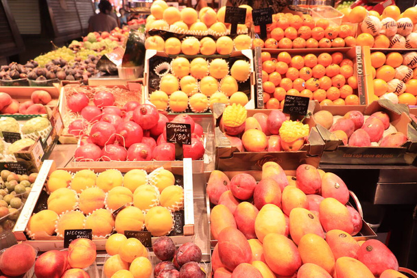 Barcelona, Španělsko - 30. září 2019: Barevné ovoce na trhu La Boqueria. Různé druhy ovoce na displeji. Text na štítcích: název produktu ve španělštině, ceny v eurech - Fotografie, Obrázek