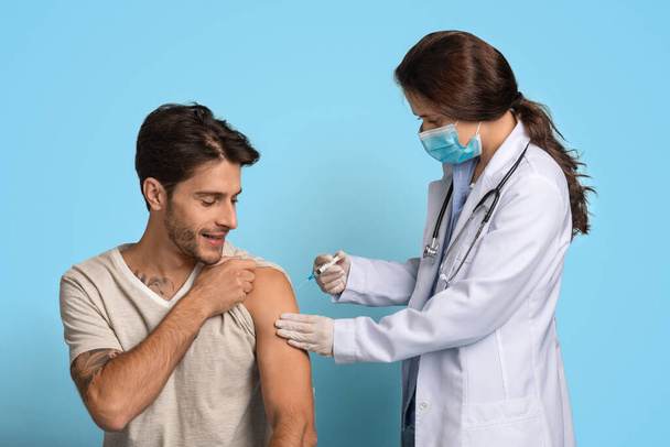 Έννοια εμβολιασμού. Γυναίκα Γιατρός με Σύριγγα Κάνοντας Ενέσιμο Εμβόλιο Σε Άνδρας Ασθενής - Φωτογραφία, εικόνα