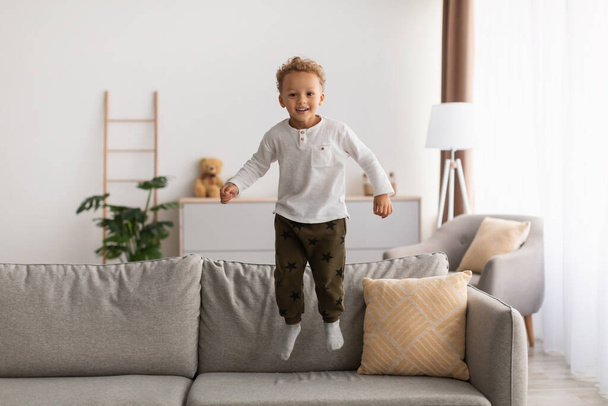 Veselý Afroameričan Little Boy Jumping se baví doma - Fotografie, Obrázek