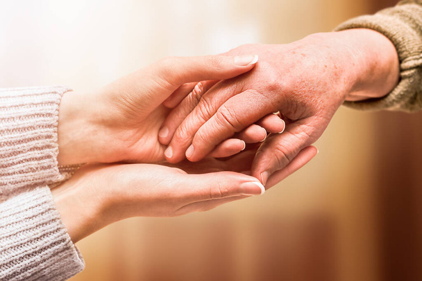 young hand holds hand of senior, care and help concept - Photo, Image