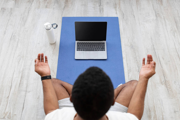 Millennial Africano americano cara olhar para laptop com tela vazia no tapete no chão com garrafa de água - Foto, Imagem