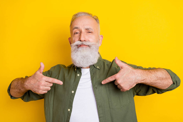 Photo portrait of senior man in green shirt pointing fingers at himself demonstrating confident isolated vivid yellow color background - Foto, Bild