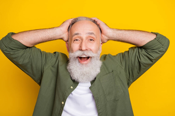 Photo portrait of grandfather keeping head smiling amazed isolated vibrant yellow color background - 写真・画像