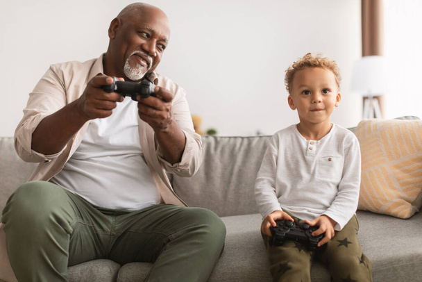 Fekete nagyapa és unokája videojátékokat játszanak, jól érzik magukat otthon - Fotó, kép
