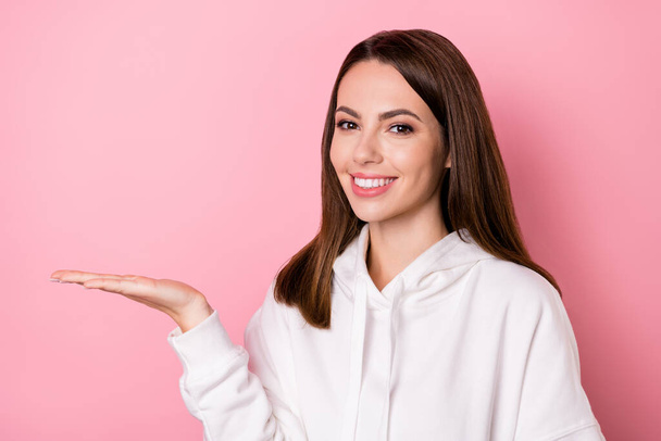 Photo of cheerful happy pretty young woman hold hand empty space good mood isolated on pink color background - Photo, image