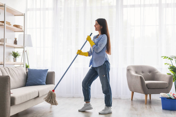 Mujer limpieza piso cantando y sosteniendo fregona - Foto, imagen