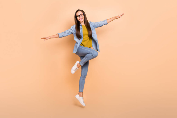 Full size photo of positive beautiful funky lady jumping spread hands plane pose isolated on beige color background - Foto, afbeelding