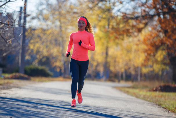 Young fitness woman running on the road in the cold morning in winter. - Foto, Imagen