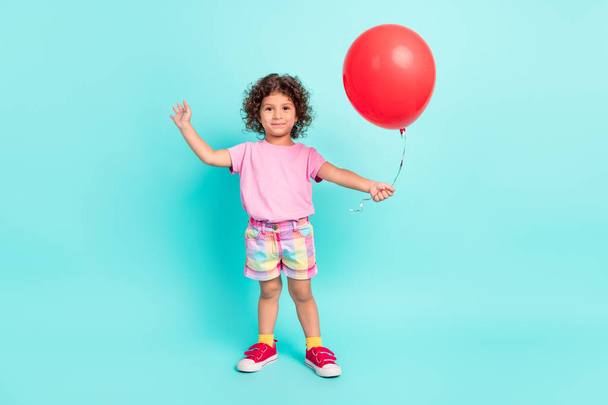 Full body photo of young little girl happy positive smile hold balloons celebration isolated over turquoise color background - Fotó, kép