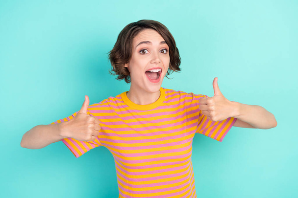 Photo of sweet impressed young woman dressed striped t-shirt smiling showing thumbs up isolated teal color background - Foto, Imagem