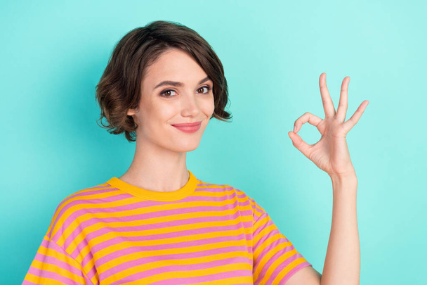 Photo of funny adorable young woman dressed striped t-shirt showing okey sign smiling isolated teal color background - Fotó, kép