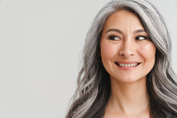 Mature shirtless woman with grey hair smiling and looking aside isolated over white background - Zdjęcie, obraz