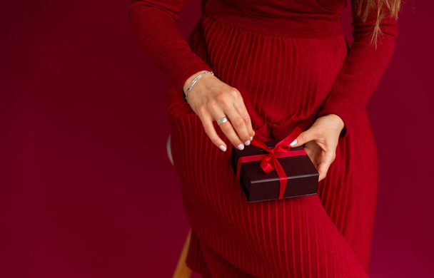 Woman wearing red opened box with present, pulling red stripe. - Foto, afbeelding