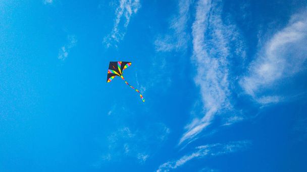 Воздушное небо. Красочная летающая игрушка. Воздушный змей летит на голубом фоне ветра. Радужный змей в летних облаках. Концепция мечты, свободы, детства - Фото, изображение