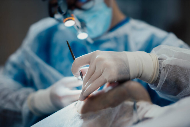 trabajo en equipo de cirujanos en el quirófano, manos en un guante de cerca con instrumentos quirúrgicos. - Foto, Imagen