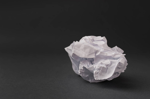 белый скомканный лист бумаги на темно-сером фоне - Фото, изображение