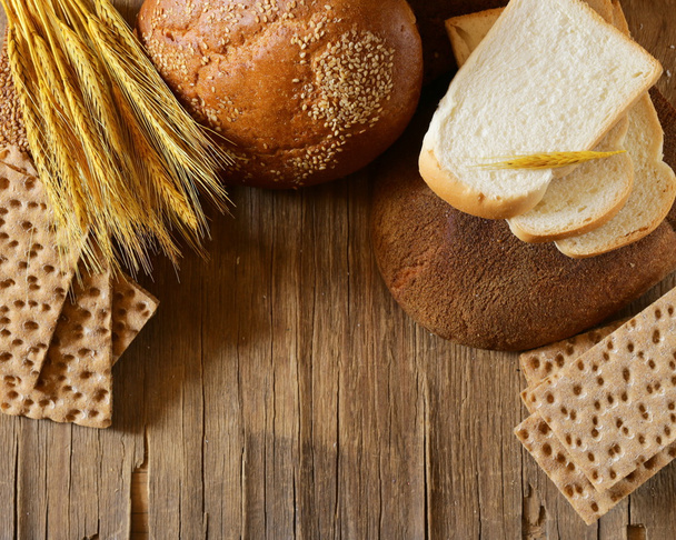 Ассортимент хлеба (ржи, цельная пшеница, для тостов) на деревянном фоне
 - Фото, изображение