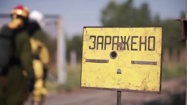 A sign warning of danger. Clip. People performing work in a dangerous area going to a gas mask on the background of a sign warning of danger - Footage, Video