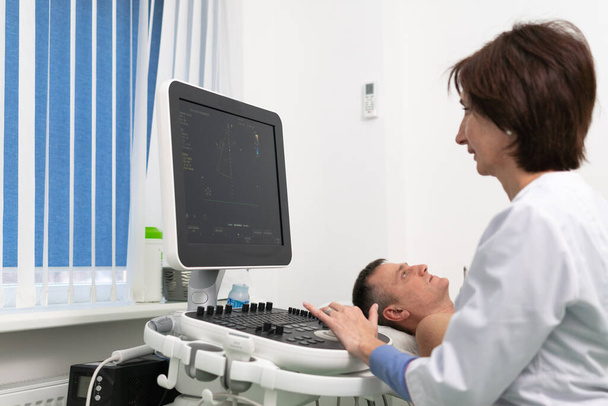 Doctor usando una máquina de ultrasonido para escanear el corazón de un paciente masculino. El cardiólogo hace de un paciente una prueba ecocardiográfica en una clínica. Paciente sometido a ecografía en el hospital - Foto, Imagen
