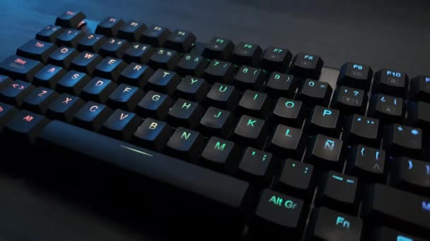 Mechanical keyboard with rgb lighting on a gray wooden desk - Footage, Video