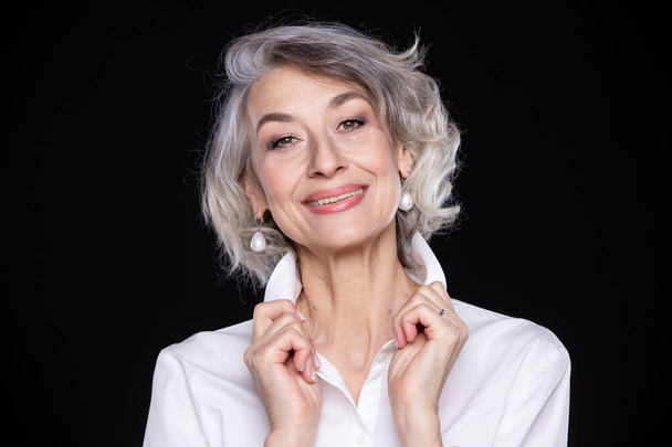 A picture of an adult mature self-confident gray-haired woman isolated on a black background - Zdjęcie, obraz