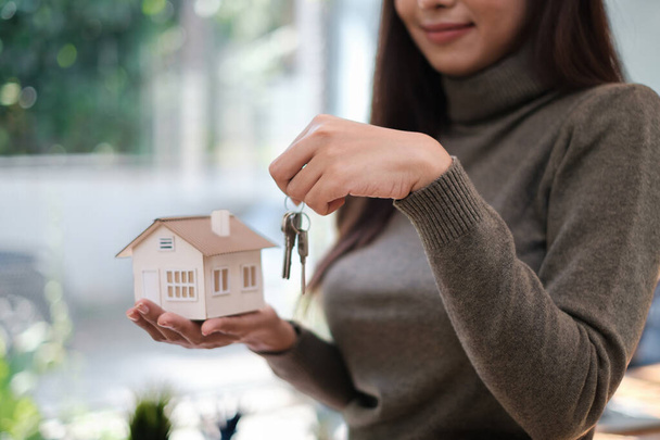 Ein Immobilienmakler demonstriert Kunden, die sich für den Kauf einer Hausversicherung interessieren, das Hausmodell. Das Konzept der Haus- und Grundversicherung. - Foto, Bild