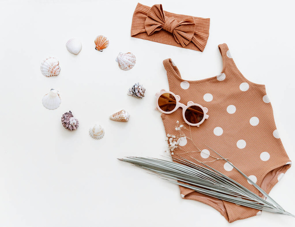 Retro swimsuit with baby accessories. Kids sunglasses, and empty blank card. Summer Fashion newborn , Holiday concept. Flat lay, top view - 写真・画像