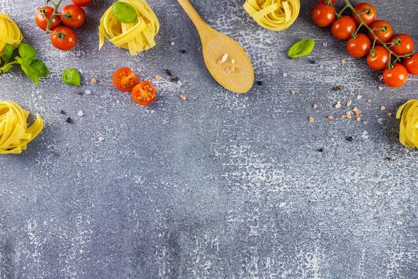 İtalyan makarnası pişirmek. Makarna malzemelerinin gri arka planında yatıyordu. Spagetti, kiraz domatesleri, baharatlar ve fesleğen. Metin için yer - Fotoğraf, Görsel