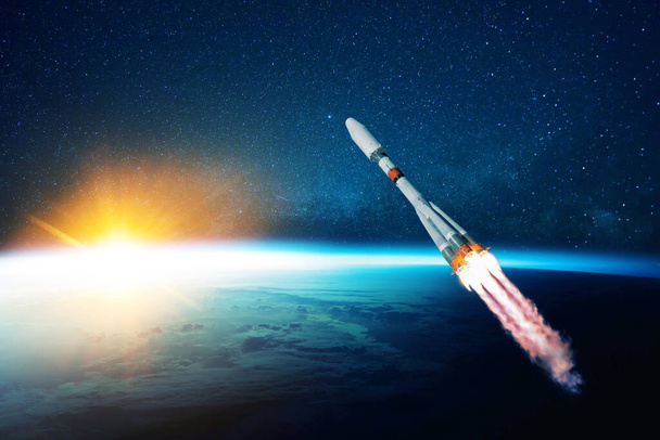 O foguete espacial levanta-se no cosmos com a fumaça e a explosão em um contexto da terra azul do planeta. Nave espacial voa no espaço com um céu estrelado perto do planeta. Início bem sucedido da missão - Foto, Imagem
