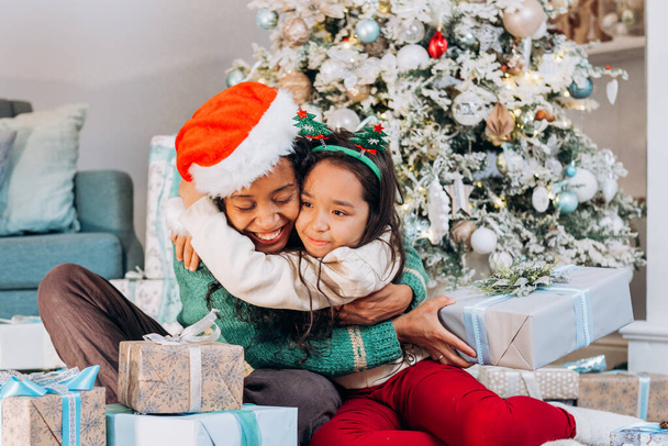 Dochter en Afro-Amerikaanse moeder knuffelen op Kerstmis - Foto, afbeelding