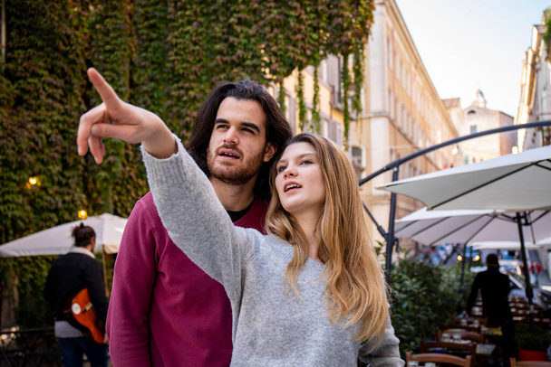 Beautiful couple traveling to Rome. A blonde woman points the way to her boyfriend. Young people are looking in the same direction. - Foto, immagini