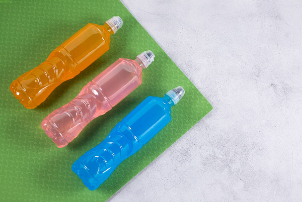 Botellas con diferentes sabores ENERGY DRINK en una esterilla deportiva. - Foto, Imagen