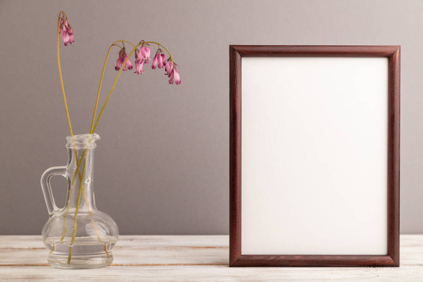 Wooden frame with pink dicentra, broken heart in glass on gray pastel background. side view, copy space, mockup, template, spring, summer minimalism concept. - Photo, Image