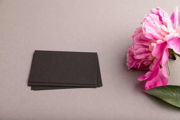 Fekete névjegykártya rózsaszín bazsarózsa virágokkal szürke pasztell háttérrel. oldalnézet, másolás, csendélet. Reggeli, reggel, tavasz. - Fotó, kép
