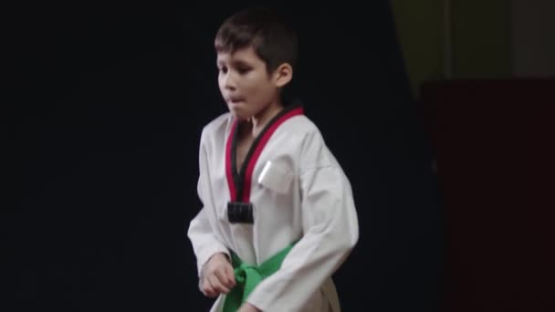 Ein kleiner Junge macht Kampfsport - springt auf der Stelle und zeigt einen Tritt aus der Drehung - Filmmaterial, Video