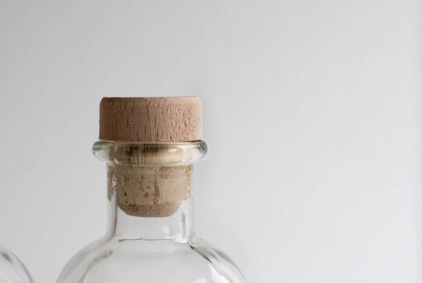 Cork stopper close up in glass transparent bottle for liquids on light background - 写真・画像