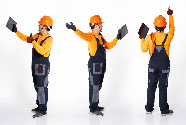 Starszy Azjata nosi pomarańczowy mundurowy kapelusz i rękawiczkę jako elektrycznego naprawiacza z kablówką. Pełna długość krótkiego stojaka męskiego online spotkanie zoom na tablecie cyfrowym, białe tło izolowane - Zdjęcie, obraz